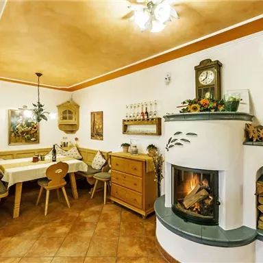 Ein gemütliches Esszimmer mit einem Kamin. Es gibt einen großen Tisch, Stühle und eine rustikale Einrichtung.