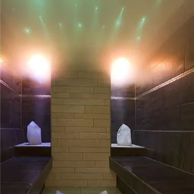 A modern wellness area with two stone benches and soft, colored lighting. Crystals are placed on both sides, creating a relaxing atmosphere.