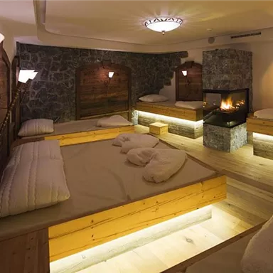 A cozy relaxation room with wooden loungers and a fireplace. Soft light creates a relaxing atmosphere.
