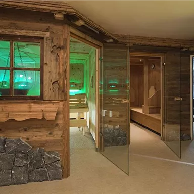 A stylish wellness room with wooden paneling and glass walls. Soft lighting creates a relaxing atmosphere.