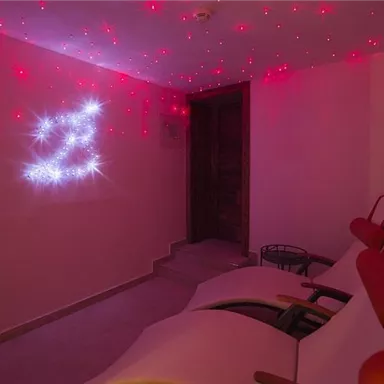 A cozy room with red lights on the ceiling and comfortable loungers. A relaxing atmosphere with radiant decor.