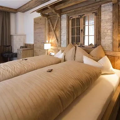 A cozy bedroom with two single beds and rustic wooden furnishings. The room features warm colors and a pleasant atmosphere.