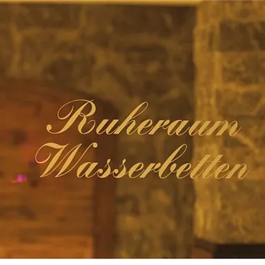 A stylish relaxation room with water beds. The wall is made of stone and wood, creating a calming atmosphere.