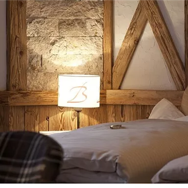A cozy bedroom with light wood and a stone wall. The soft lighting creates a relaxed atmosphere.