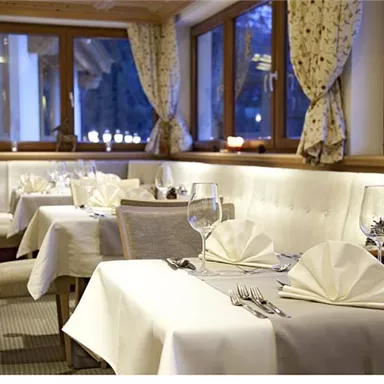 An elegant restaurant with beautifully set tables and cozy windows. The soft lighting creates an inviting atmosphere.