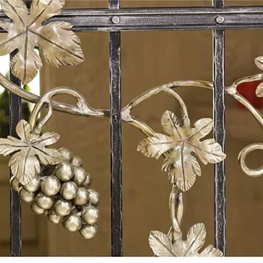 An artistic metal fence with leaf and grape motifs. The golden color adds elegance to the design and creates an inviting atmosphere.