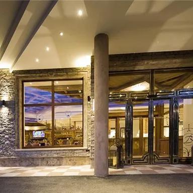 A modern restaurant with large windows and a stylish atmosphere. Warm light and an inviting ambiance create a pleasant impression.