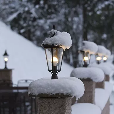 A wintry scene with lanterns covered in snow. In the background, you can see snow-covered trees and an inviting atmosphere.