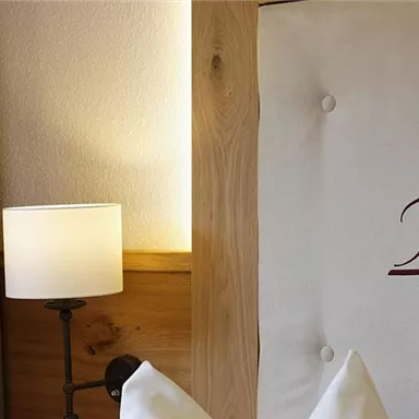 A cozy bedroom with a stylish headboard and a modern table lamp. The warm colors create an inviting atmosphere.