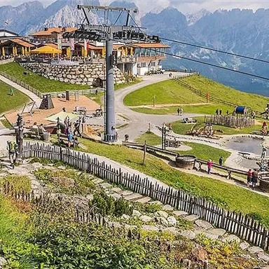 Eine malerische Berglandschaft mit einer Seilbahn und einem Restaurant. Viele Menschen genießen die Aussicht und die Aktivitäten im Freien.