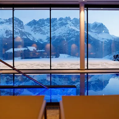 A beautiful swimming pool with a view of snow-covered mountains. The large window front offers an impressive view of the winter landscape.