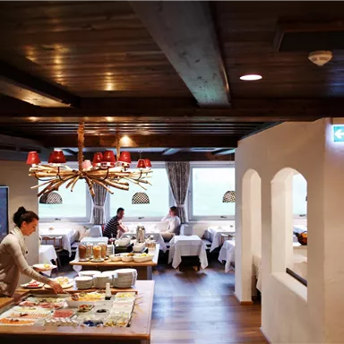 A cozy restaurant with warm lighting and rustic wooden decor. Guests enjoy their meals while the staff is at work.