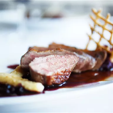 A tasty dish with tender meat, served with fruit compote and crispy sides. The presentation is stylish and appealing.