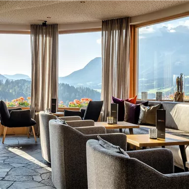 An elegant lounge with large windows and a view of the mountains. Cozy seating and a warm atmosphere invite relaxation.