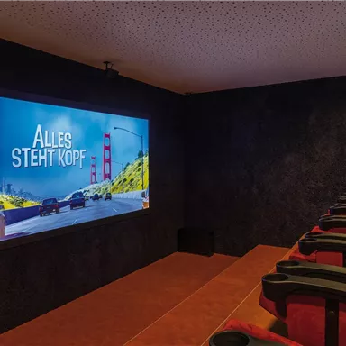 A small home theater room with red seating and a large screen. The title "INSIDE OUT" is on the screen.