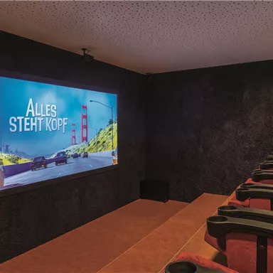 A cozy home theater with red seats and a large screen. The movie "Inside Out" is shown on the screen.
