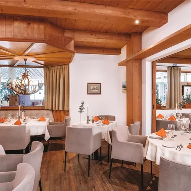 An elegant restaurant with wooden walls and a cozy atmosphere. The tables are set with white tablecloths and orange napkins.