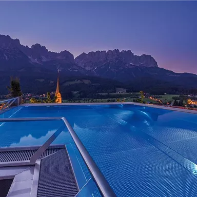 A stunning pool with a view of the mountains and a clear evening sky. The surroundings are calm and picturesque, perfect for relaxing.