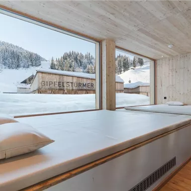 A modern room with wooden paneling and large windows. Outside, you can see snow-covered mountains and a serene landscape.