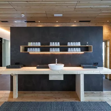 A modern sink in a stylish room with wooden walls. The large wooden table provides space for various utensils and creates a relaxed atmosphere.