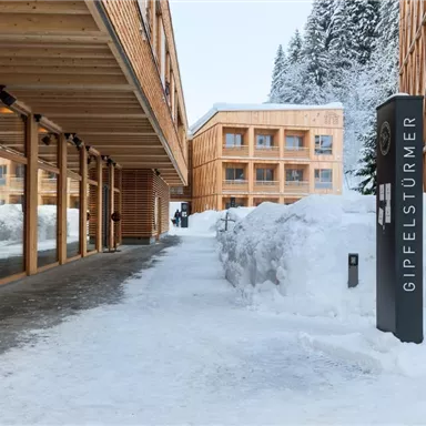 A modern wooden building in a snowy landscape. The snow lies thick on the ground and a clear, peaceful atmosphere can be seen.
