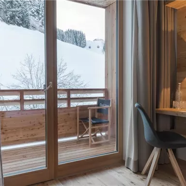 A modern room with a view of a snowy balcony. The room is bright and minimally designed.