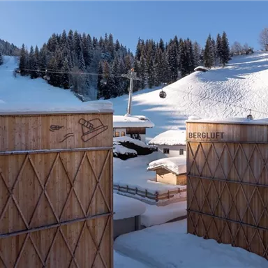 A winter mountain village with snow-covered hills and a cable car. Wooden buildings with traditional design complement the picturesque landscape.