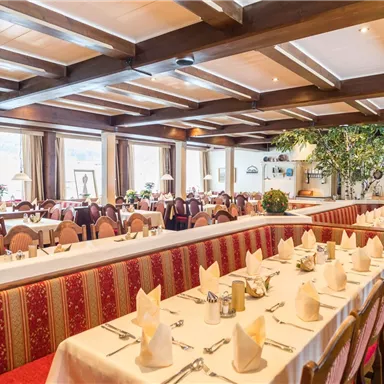 Ein gemütliches Restaurant mit eleganten Tischdecken und geschmackvoller Einrichtung. Große Fenster bieten einen Blick auf das Restaurant und sorgen für eine angenehme Atmosphäre.