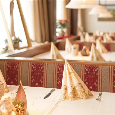 Ein elegantes Restaurant mit gepflegten Tischen und dekorierten Servietten. Die warme Atmosphäre wird durch die sanfte Beleuchtung unterstützt.