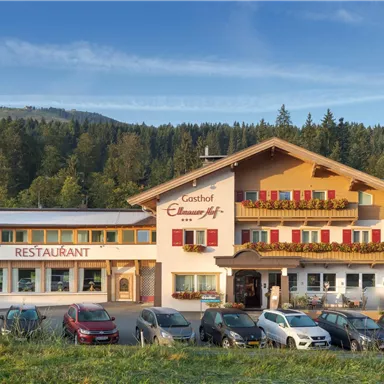 Ein charmantes Gasthaus mit Restaurant, umgeben von einer malerischen Landschaft. Das Gebäude hat bunte Fensterläden und einen einladenden Eingangsbereich.