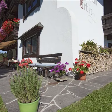 A traditional house with colorful flowers and a beautiful garden. The terrace invites you to relax outdoors.