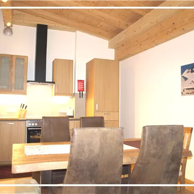 Eine moderne küche mit Holzregalen und einem Esstisch. Die Einrichtung ist gemütlich und einladend.