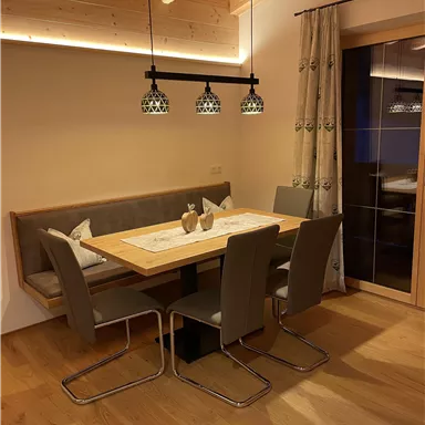 Ein gemütlicher Essbereich mit einem Holzspeiseplatz und modernen Stühlen. Die Beleuchtung sorgt für eine warme Atmosphäre.