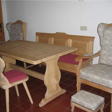 A cozy dining area with a wooden table and matching chairs. The furniture is made of light wood and has padded seats.