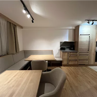 Eine moderne Küche mit Essbereich aus Holz. Helle Möbel und eine einladende Atmosphäre schaffen Gemütlichkeit.