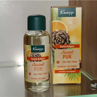 Ein Fläschchen Sauna-Auszug von Kneipp steht neben einer Verpackung. Das Produkt trägt die Bezeichnung "Auszeit PUR" und enthält ätherische Öle.