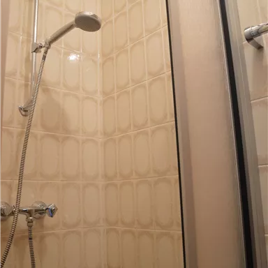 Eine Dusche mit einer klaren Duschwand. Die Wände sind mit hellen Fliesen dekoriert.