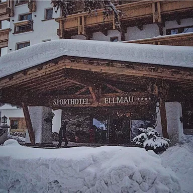 A snow-covered hotel with an inviting entrance. The surroundings are designed to be wintry and cozy.