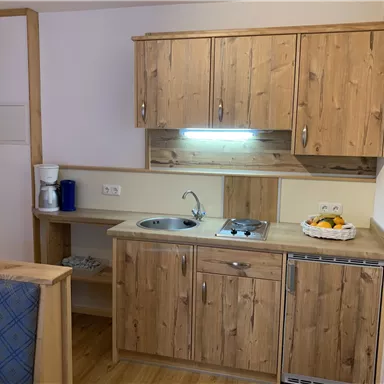 Eine moderne Küchenecke mit Holzschränken und allen notwendigen Geräten. Die Küche ist hell und freundlich gestaltet.