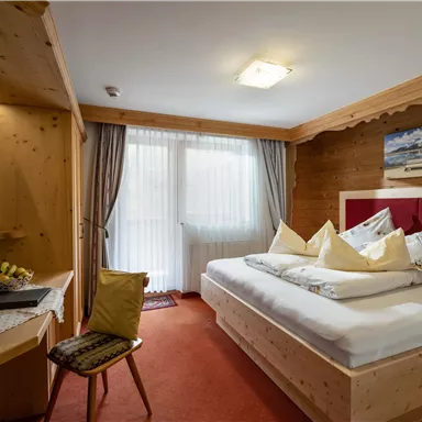Ein gemütliches Hotelzimmer mit einem Doppelbett und Holzvertäfelungen. Das Zimmer ist hell und bietet eine schöne Aussicht durch das Fenster.