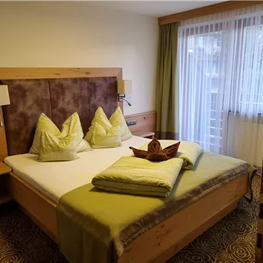 A cozy bedroom with a large bed and decorative pillows. The room has plenty of natural light and a calm atmosphere.