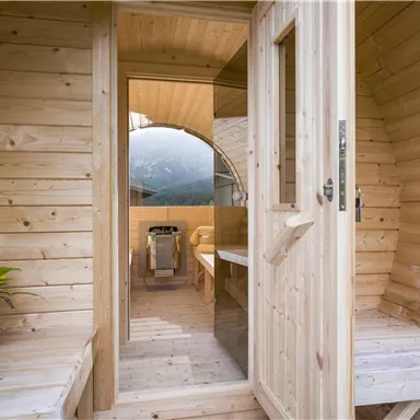 Ein gemütlicher Holzhütten-Eingang mit einer schönen Aussicht auf die Natur. Innen gibt es einen Tisch und eine Kochgelegenheit.