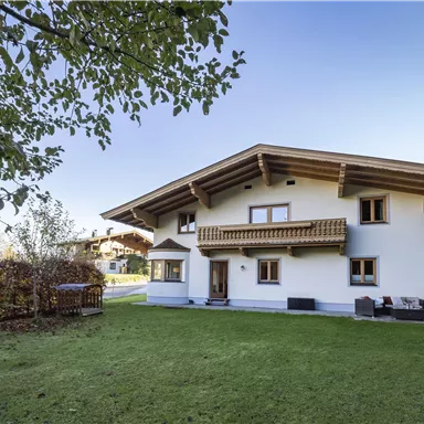Ein modernes Haus mit einem großen Garten und einer schönen Terrasse. Umgeben von Bäumen und einer ruhigen Umgebung.