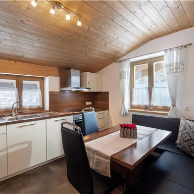 Eine moderne Küche mit Holzverkleidung und einem Essbereich. Die warmen Farben schaffen eine einladende Atmosphäre.