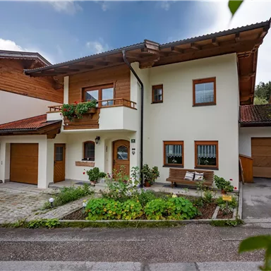 Ein modernes Haus mit einem schönen Garten. Die Fassade ist hell, und es gibt einen Balkon sowie eine Garage.