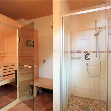 Eine moderne Sauna auf der linken Seite und eine Dusche auf der rechten Seite. Die Wände sind aus Holz und es gibt beige Fliesen im Badezimmer.