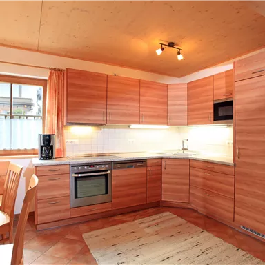 Eine moderne Küche mit Holzschränken und einem hellen, einladenden Ambiente. Der Essbereich ist gemütlich mit einem Tisch und Stühlen ausgestattet.