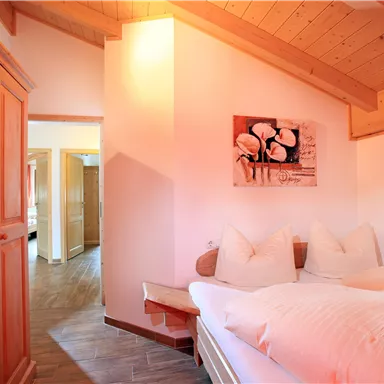 Ein gemütliches Schlafzimmer mit Holzdecke und -möbeln. Das Zimmer hat ein großes Bett mit Kissen und ein Bild an der Wand.