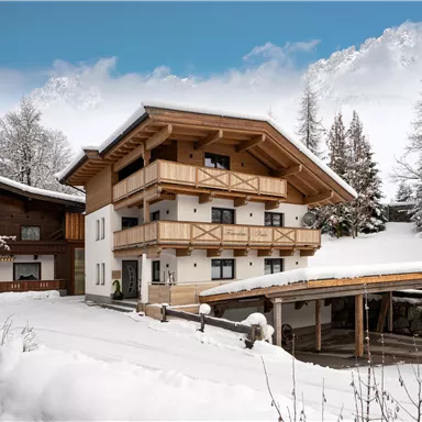 Ein wunderschönes Haus im alpinen Stil, umgeben von einer schneebedeckten Landschaft. Die klare, blaue Himmel sorgt für eine friedliche Winteratmosphäre.