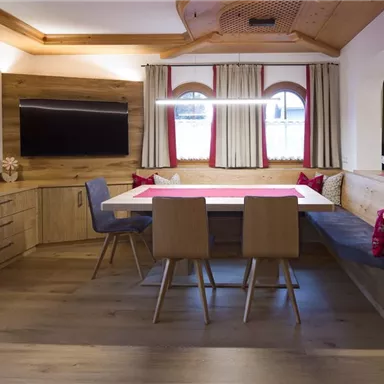 A modern living room with wood paneling. There is a dining table and a cozy seating area.